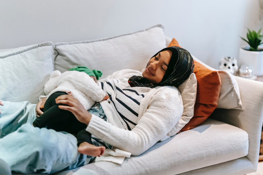 mother and baby lying on couch