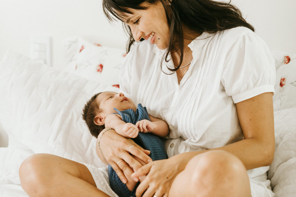 mother sitting in bed holding her baby